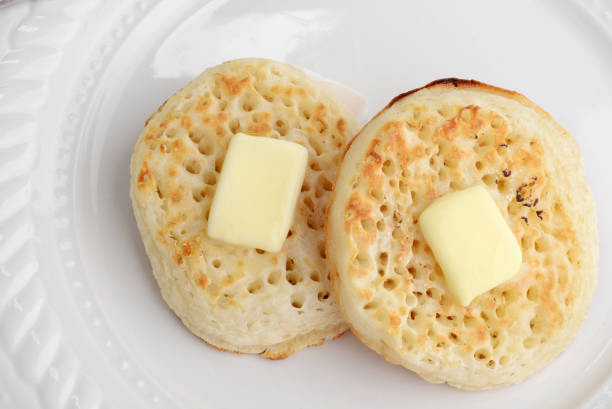 closeup top view english crumpets with butter closeup top view english crumpets with butter on a white plate Crumpet with Butter stock pictures, royalty-free photos & images
