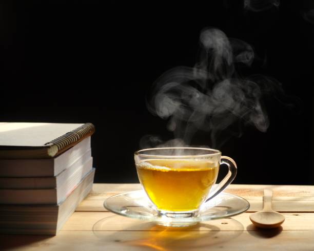 istock Hot tea with smoke on wooden table, black background, hot drink 1156279971