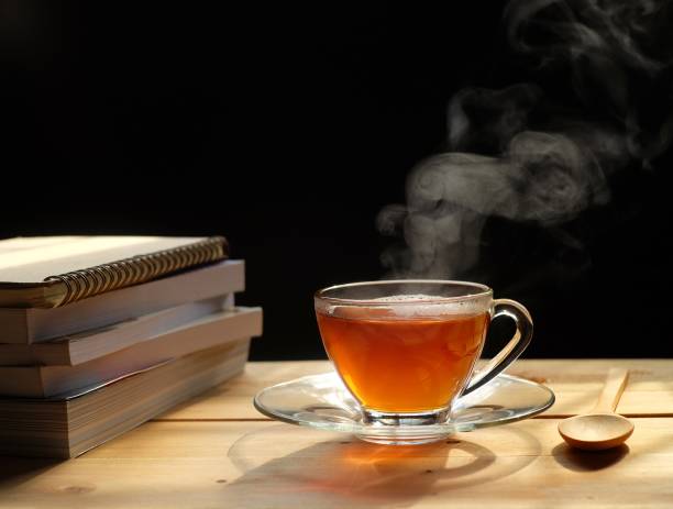 istock Hot tea with smoke on wooden table, black background, hot drink 1156280011