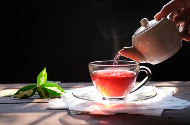 istock Hot tea with smoke on wooden table, black background, hot drink 1156280024