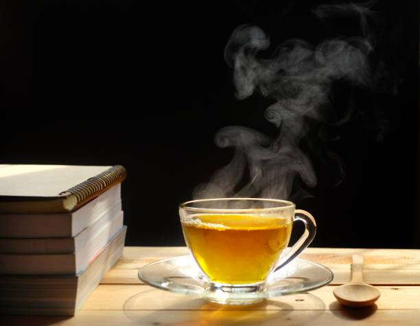 istock Hot tea with smoke on wooden table, black background, hot drink 1156280036
