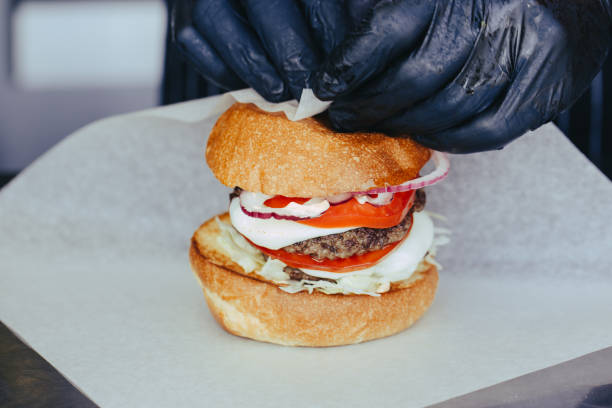 istock Cook preparing burger adding the sauce on the cream cheese. Three burgers. 1156280790