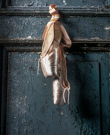 Old used pink ballet shoes hanging -