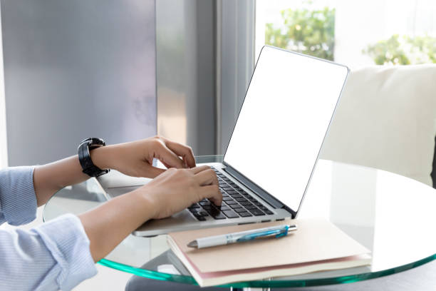 istock Woman's hands using laptop with blank screen on glass desk in home office 1156286314