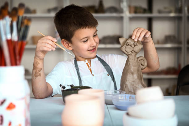 criança na forma do molde da classe da cerâmica e na argila da pintura - potter human hand craftsperson molding - fotografias e filmes do acervo