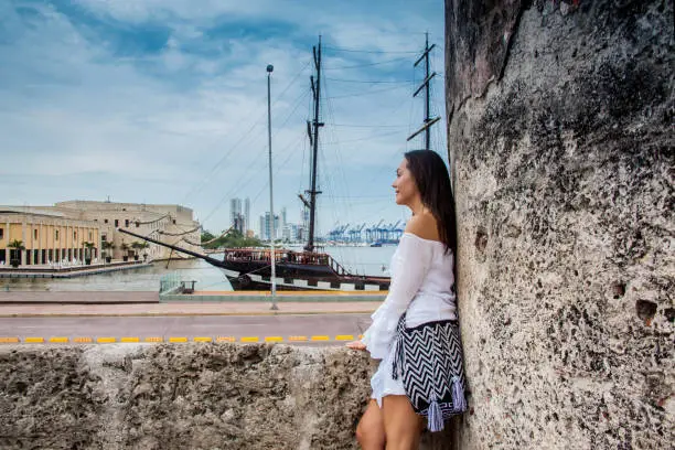 Beautiful woman standing at the walls of Cartagena de Indias looking to the bay