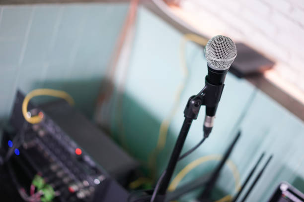 istock Microphone. A closed up details and soft focus of a microphone with abstract blurred background of brick wall and other sound equipment controller. 1156297346
