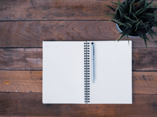 istock A pen on blank of notebook is open on wooden tabl 1156300026