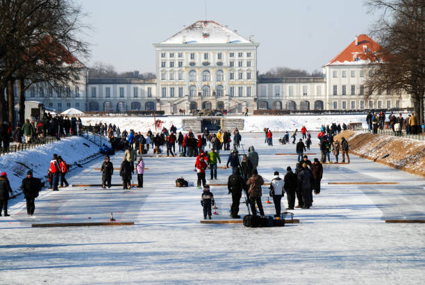 Munich, Germany, 02/05/2012\nwinter scene with ice skaters on frozen kanal in front of nymphenburg castle
