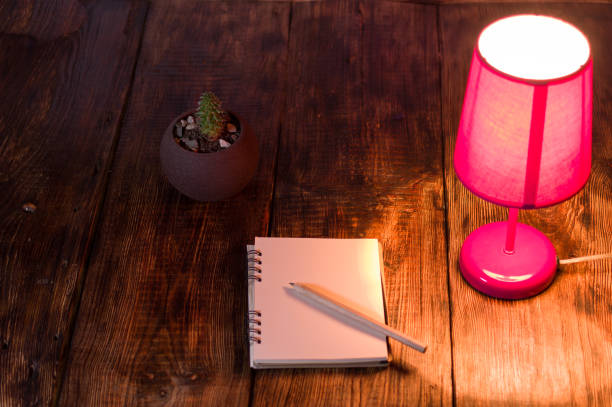 istock Pink night light and notebook with pencil. Night light on the desk. 1156305541