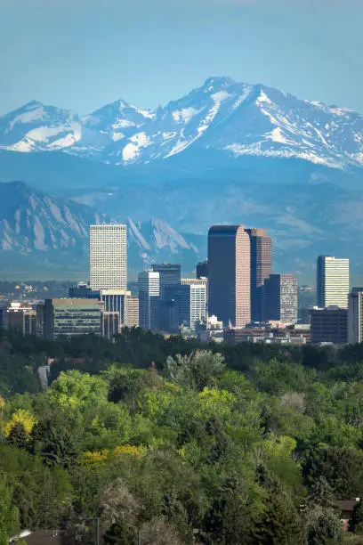 The snow covered Rocky Mountains and Longs Peak rises over the Boulder Flatirons and Downtown Denver skyscrapers, hotels, office and apartment buildings.