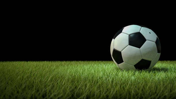 istock Soccer ball on green grass, on black background 1156305756