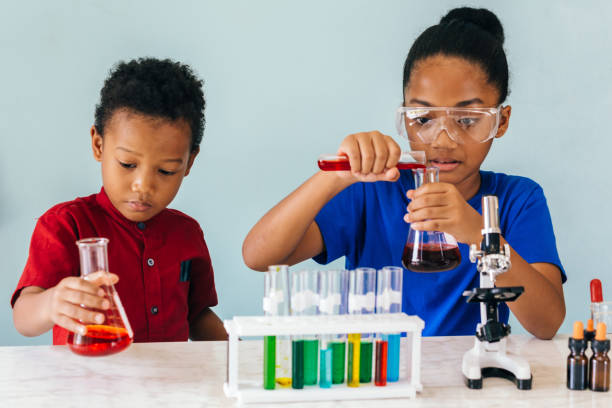 Two African American mixed kids testing chemistry lab experiment stock photo