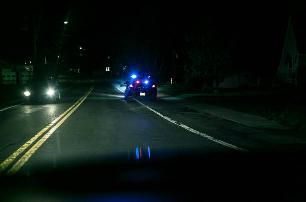 voiture de bord de route tirée au-dessus par la police la nuit - car pursuit chasing night photos et images de collection