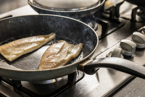 frischer fisch auf bratpfanne in der küche - flounder fillet seafood meal stock-fotos und bilder