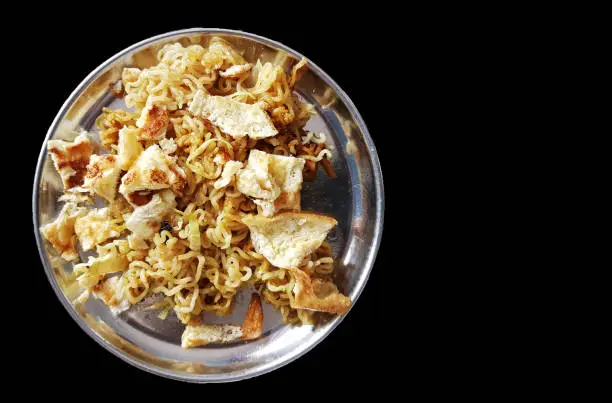 fried noodle on a steel plate with fried eggs in black background with space for text