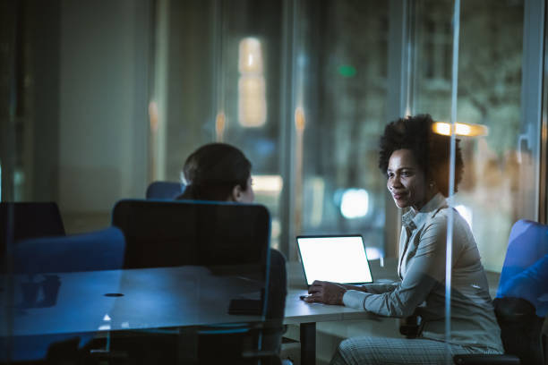 istock Smiling businesswomen talking while working late in the office. 1156313180