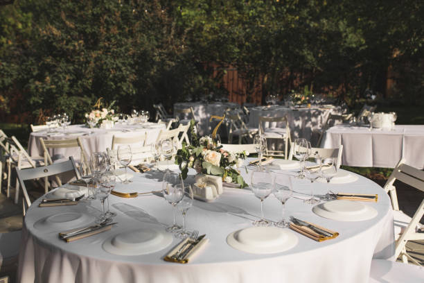 istock Wedding table setting decorated with fresh flowers in a brass vase. Wedding floristry. Banquet table for guests outdoors with a view of green nature. Bouquet with roses, eustoma and eucalyptus leaves. 1156313213
