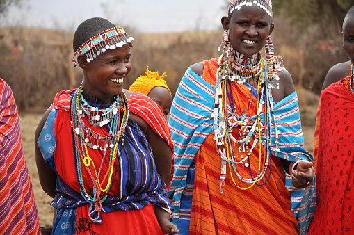 Amboseli National Park, Kenya - September, 2014: Portarait of group of african women with traditional colorful ornaments (necklace, earrings) smiling and greeting tourists with traditional jumping dance