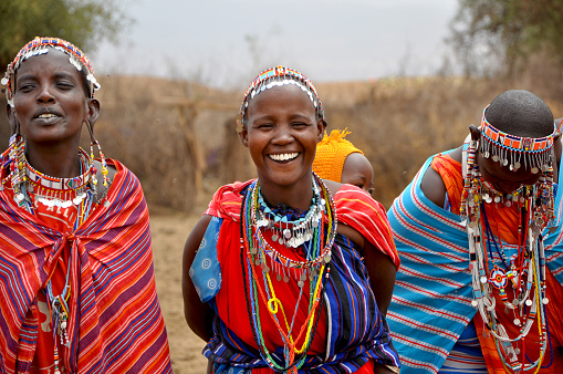 Amboseli National Park, Kenya - September, 2014: Portarait of three african women with traditional colorful ornaments (necklace, earrings) smiling and greeting tourists with traditional jumping dance