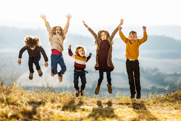 istock Happy kids having fun while jumping and screaming in a meadow. 1156314074