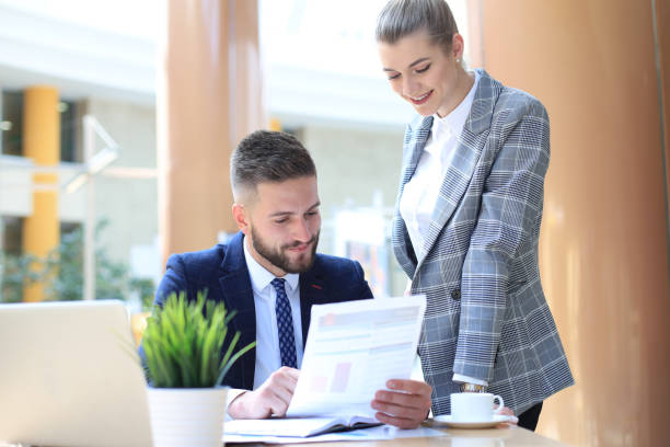 istock Two young business people using laptop in office while collaborating on startup project. 1156315619
