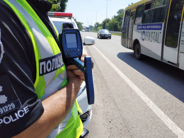 ウクライナの交通警察官は、高速道路の背景にスピードチェックのためのスピードガンを保持しています。選択的な焦点、体の一部。 - editorial eastern europe europe reflection ストックフォトと画像