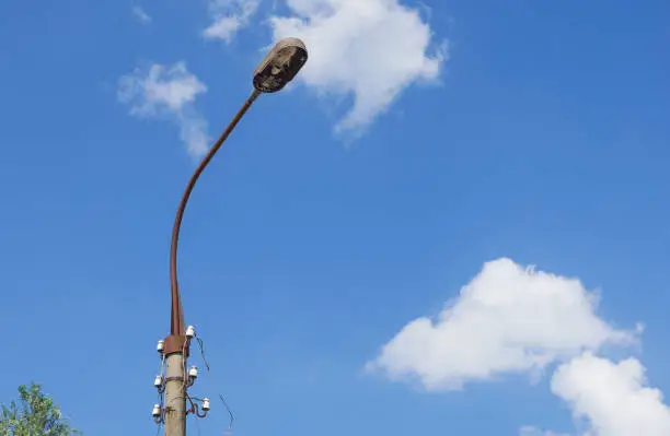 Photo of Old broken, abandoned street lamp and torn wires against the sky. Abstract image with copy-space.