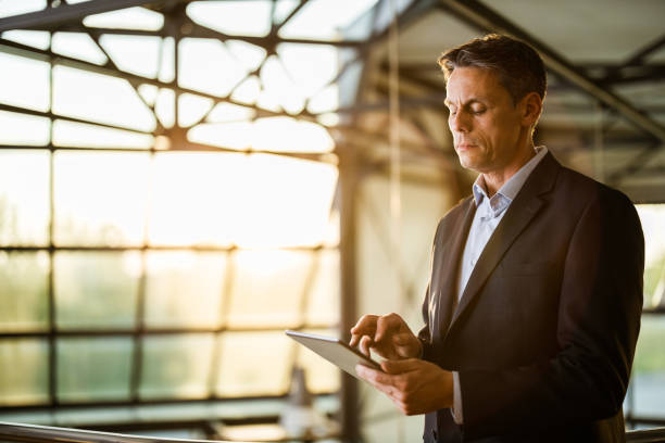 istock Mid adult male entrepreneur reading an e-mail on touchpad in a hallway. 1156318976