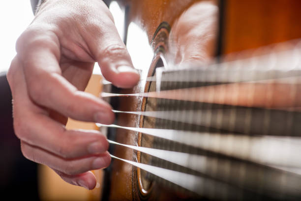 istock adult white guy playing an acoustic guitar. Backlit shooting 1156319896