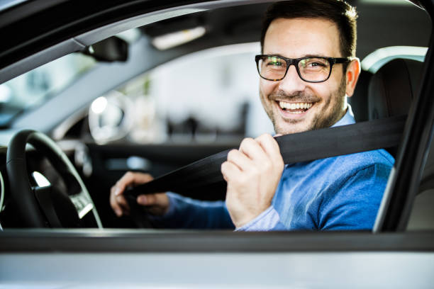homme d'affaires heureux attachant la ceinture de sécurité avant son voyage en voiture. - fastening photos et images de collection