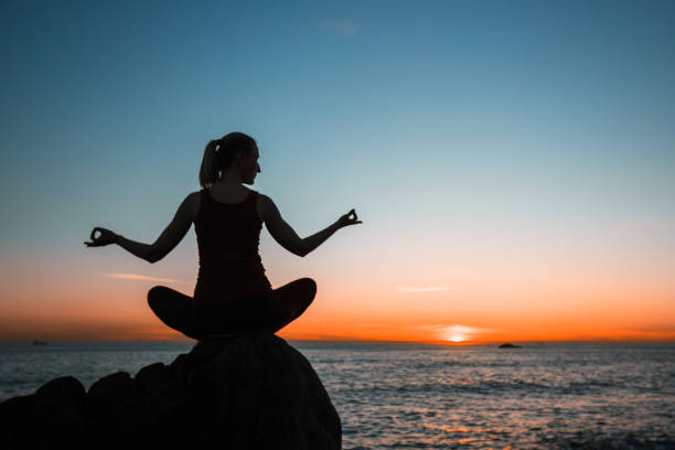 istock Silhouette young woman practicing yoga on the sunset ocean beach. Tranquility. 1156322701