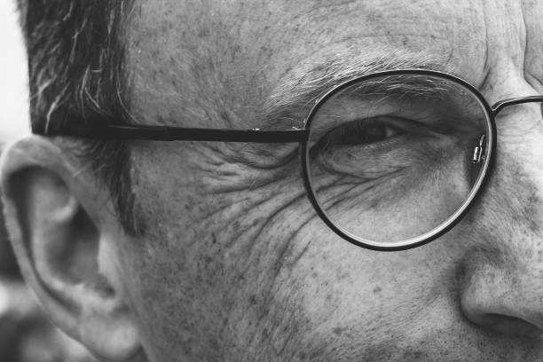 vista parcial da face do homem envelhecido médio - staring black and white glasses human face - fotografias e filmes do acervo