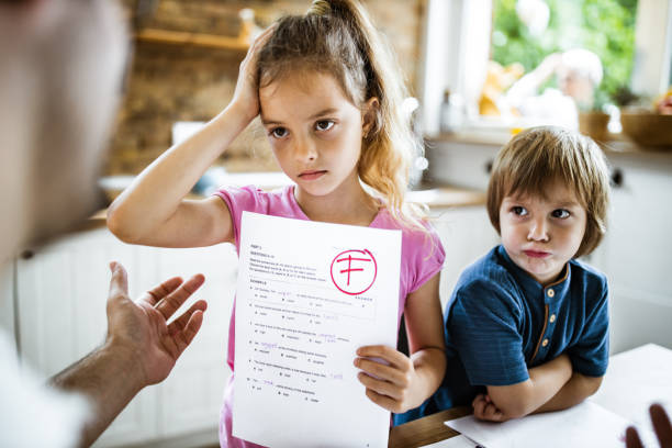 I've got an F on my test results! Little girl feeling sad while showing her parent a negative test results at home. educational test results stock pictures, royalty-free photos & images