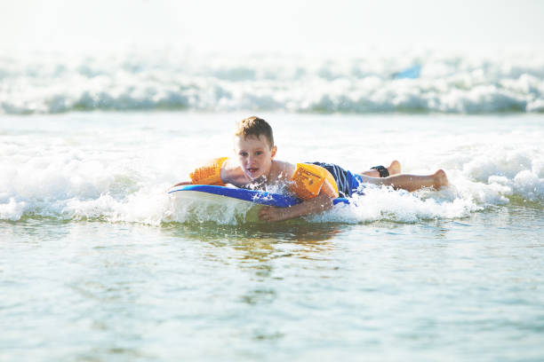 istock Little boy bodyboarding at the sea 1156325683