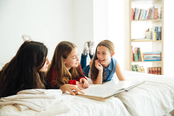 istock Three Happy Sisters Lying in Bedroom and Reading a Book. 1156328628