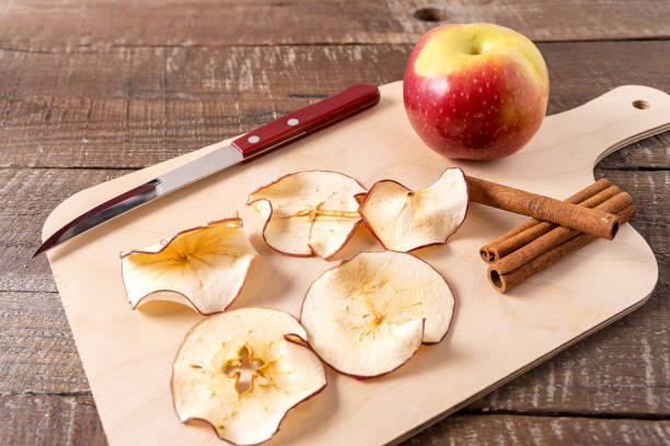 istock Dried apple chips , raw apple , cinnamon sticks on cooking board over wood background. 1156332999