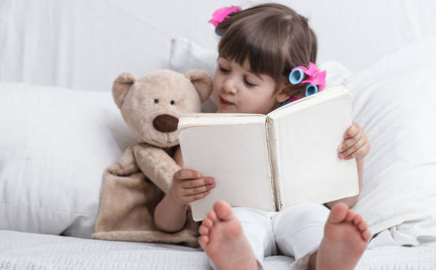 istock Cute little girl smiling while lying in a cozy white bed 1156333229