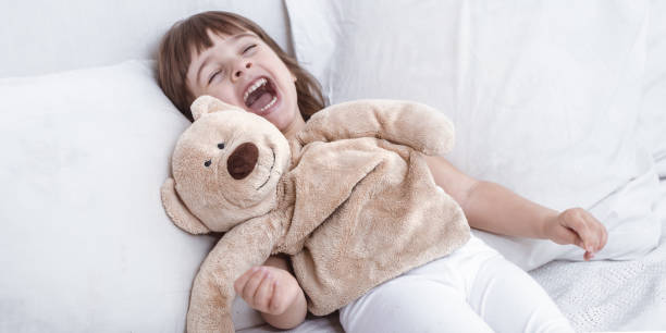 istock Cute little girl smiling while lying in a cozy white bed 1156333230
