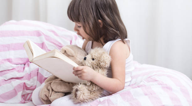 istock Cute little girl smiling while lying in a cozy white bed 1156333232