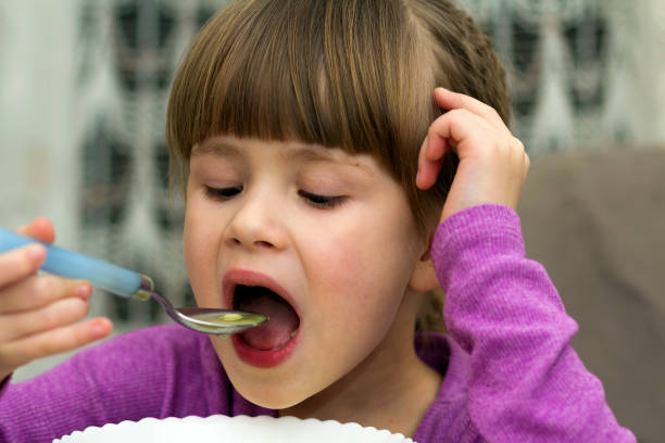 istock Child girl eating soup from a plate with a spoon 1156340899