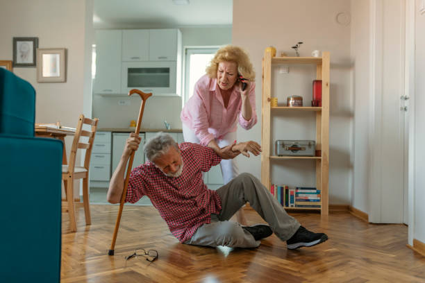 marito anziano seduto a terra mentre la moglie in pensione parla su smartphone - falling people tripping senior adult foto e immagini stock