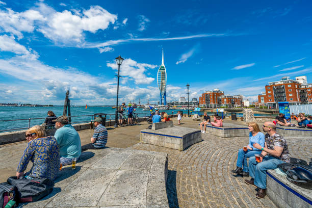 People sitting at the waterfront area with the Spinnaker Tower building in the distance on May 25, 2019 in Portsmouth