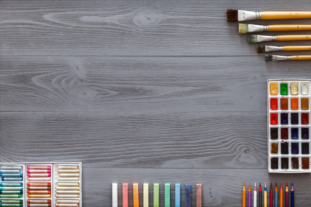 istock Art creative table background with watercolor paints palette paintbrushes pencils crayons supplies tools on grey wooden desk, artist gray design workspace top view from above, flat lay, copy space 1156351191
