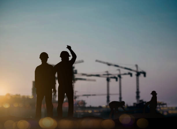 istock silhouette engineer looking Loaders and trucks in a building site over Blurred construction worker on construction site 1156351220