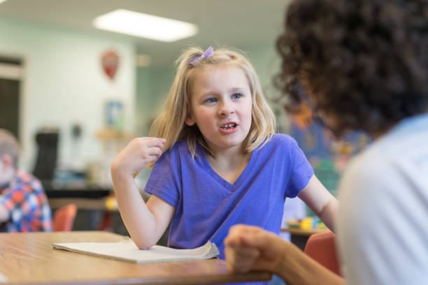 istock Elementary-age girl talking with her teacher in the classroom 1156352468