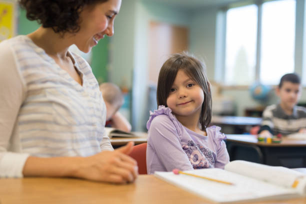 istock First grade girl talking with her teacher in the classroom 1156352475