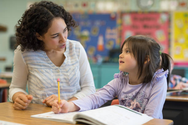 istock First grade girl talking with her teacher in the classroom 1156352476
