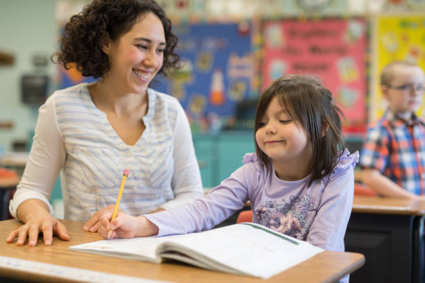 istock First grade girl talking with her teacher in the classroom 1156352477