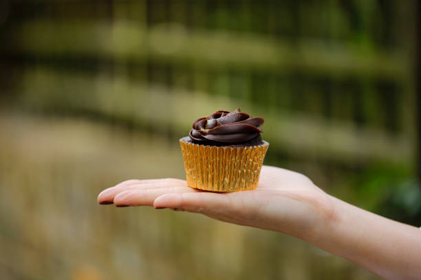 istock Woman holding tasty chocolate cupcake 1156355156